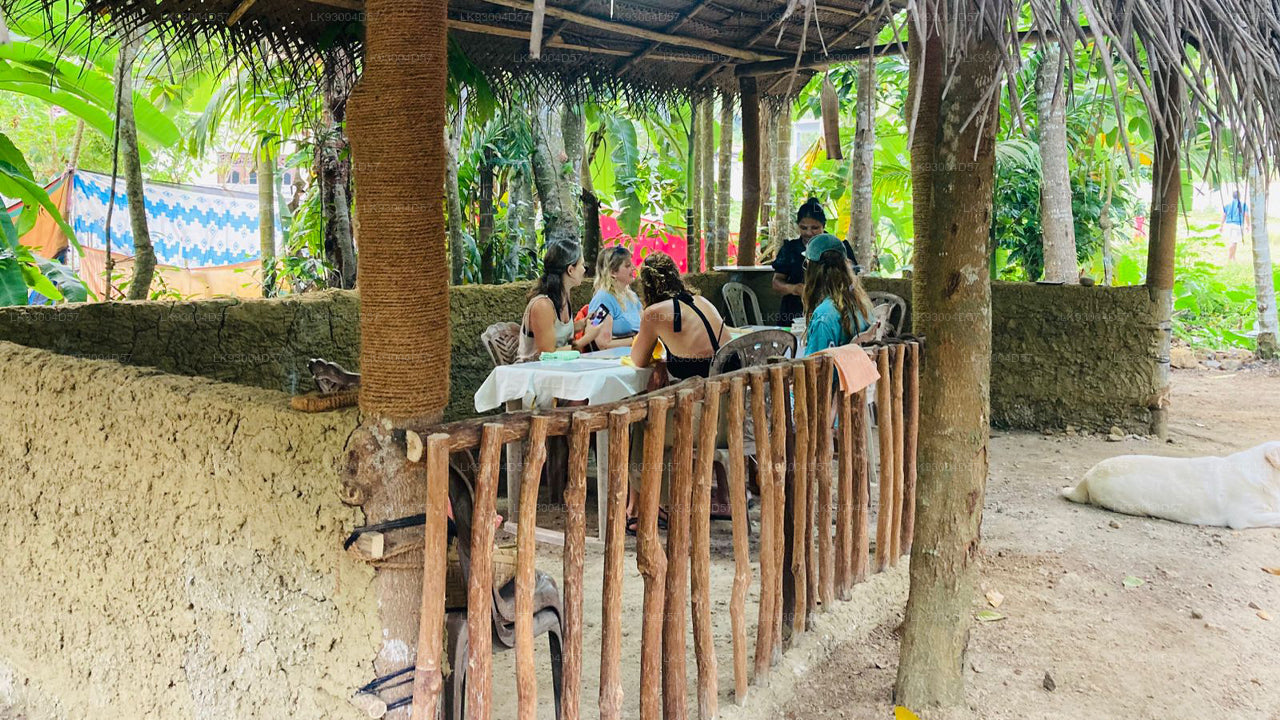 People sitting under a thatched roof in a tropical setting with palm trees.