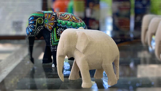 Two elephant figurines on a reflective surface with a blurred background