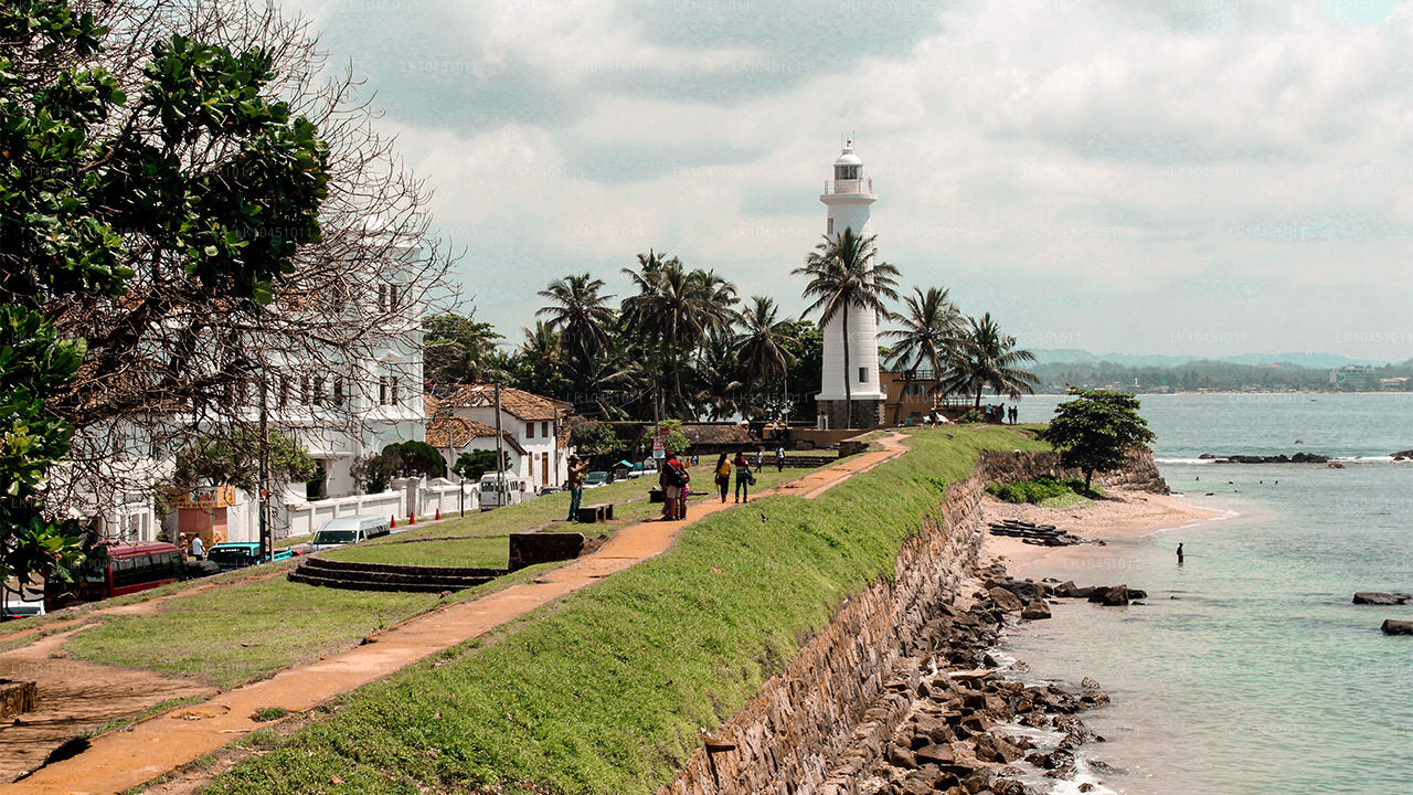 Galle Lighthouse surrounded by palm trees on the fort walls overlooking the Indian Ocean in Sri Lanka.